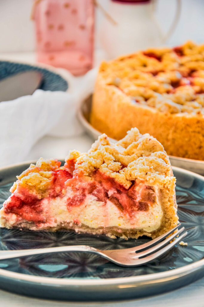 Ein Stück Rhabarber-Streuselkuchen mit Erdbeeren und Quark-Puddingcreme.