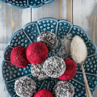 Schoko Bliss Balls mit Kokos und Himbeere auf einem blauen Teller. Aufnahmen von oben.