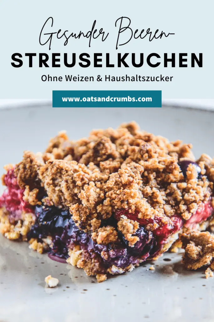 Ein Stück gesunder, zuckerfreier Beeren-Streuselkuchen auf einem grauen Teller. Ansicht im 45-Grad-Winkel und von oben. Sehr knusprige Textur.
