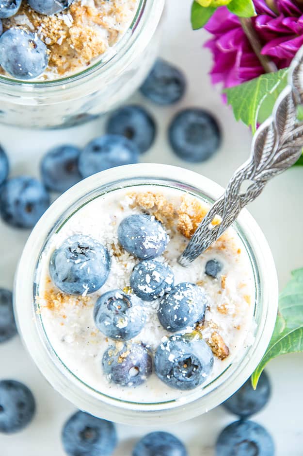 Blueberry Cheesecake Overnight Oats mit Vollkornbutterkeksen, Frischkäse, Zitrone, Ahornsirup und Heidelbeeren
