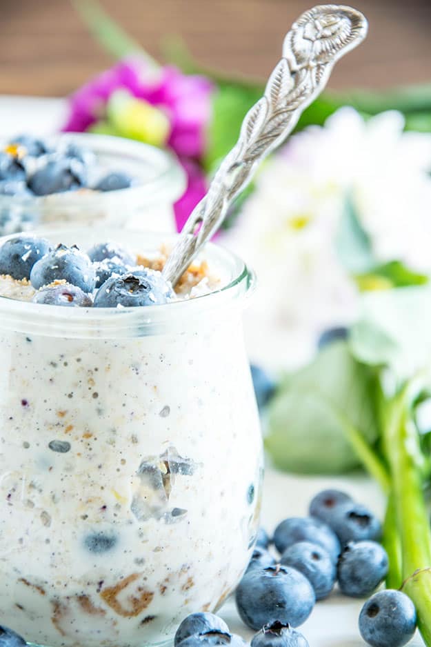 Blueberry Cheesecake Overnight Oats mit Vollkornbutterkeksen, Frischkäse, Zitrone, Ahornsirup und Heidelbeeren