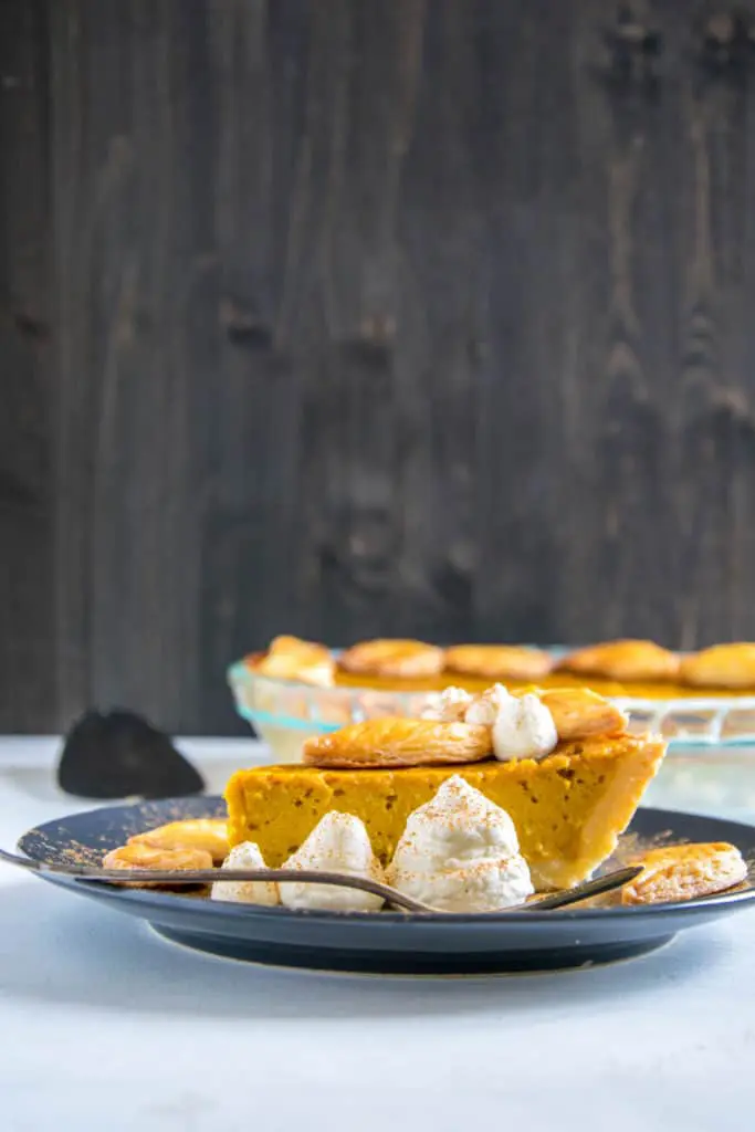 Ein Stück Pumpkin Pie mit Herbstblätter-Deko und Zimt-Sahne