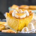 Ein Stück Pumpkin Pie mit Herbstblätter-Deko und Zimt-Sahne