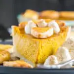 Ein Stück Pumpkin Pie mit Herbstblätter-Deko und Zimt-Sahne