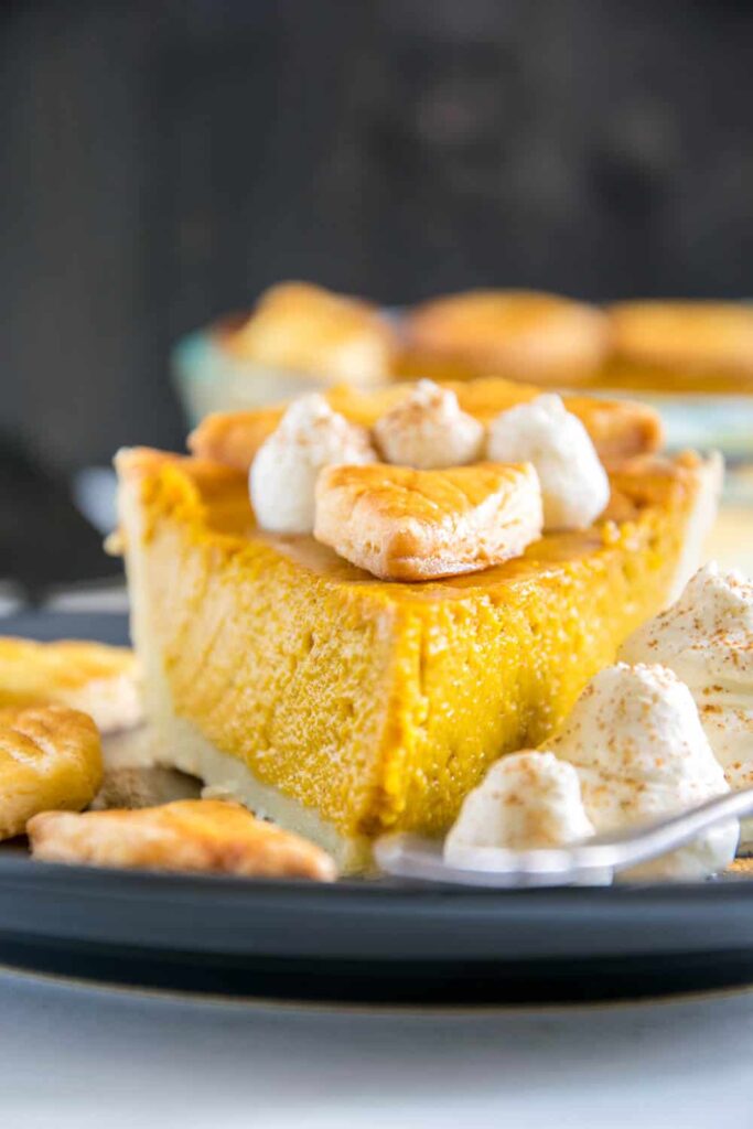 Ein Stück Pumpkin Pie mit Herbstblätter-Deko und Zimt-Sahne