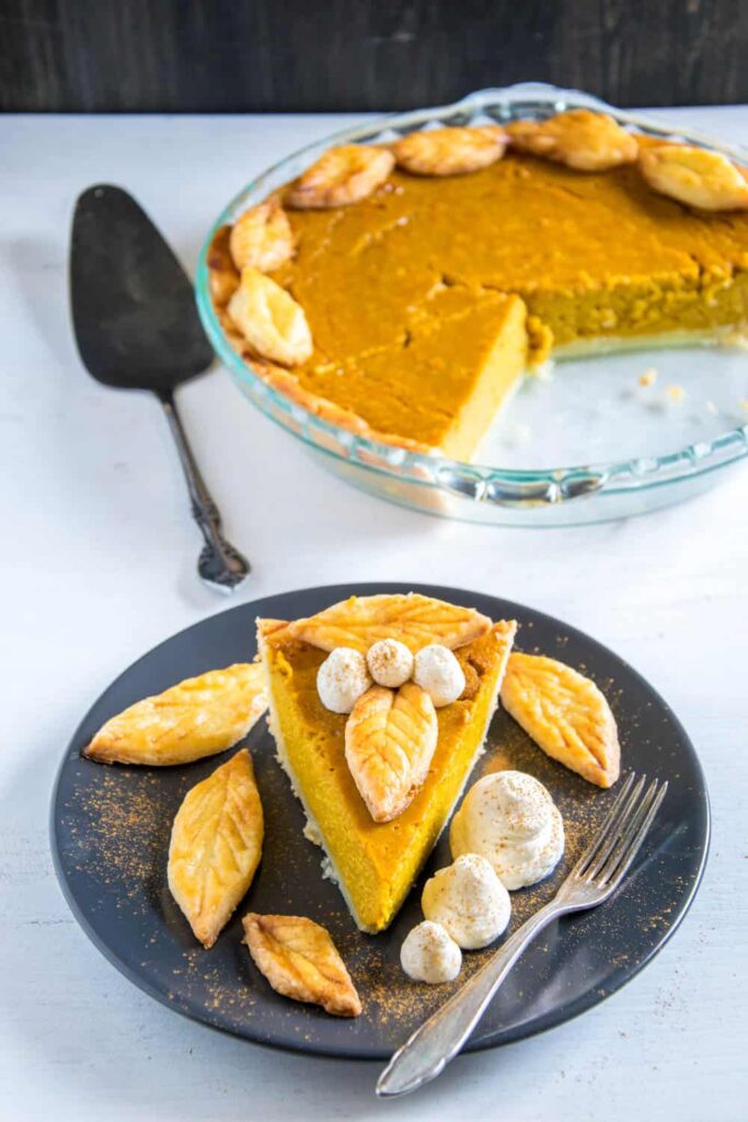 Ein Stück Pumpkin Pie mit Herbstblätter-Deko und Zimt-Sahne