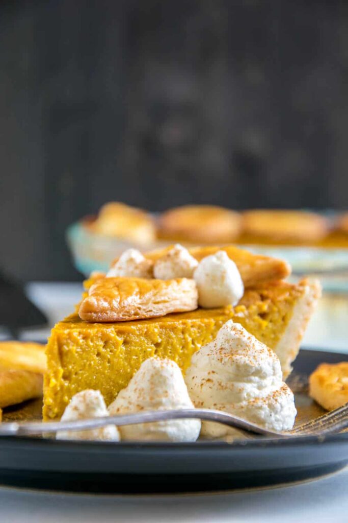 Ein Stück Pumpkin Pie mit Herbstblätter-Deko und Zimt-Sahne