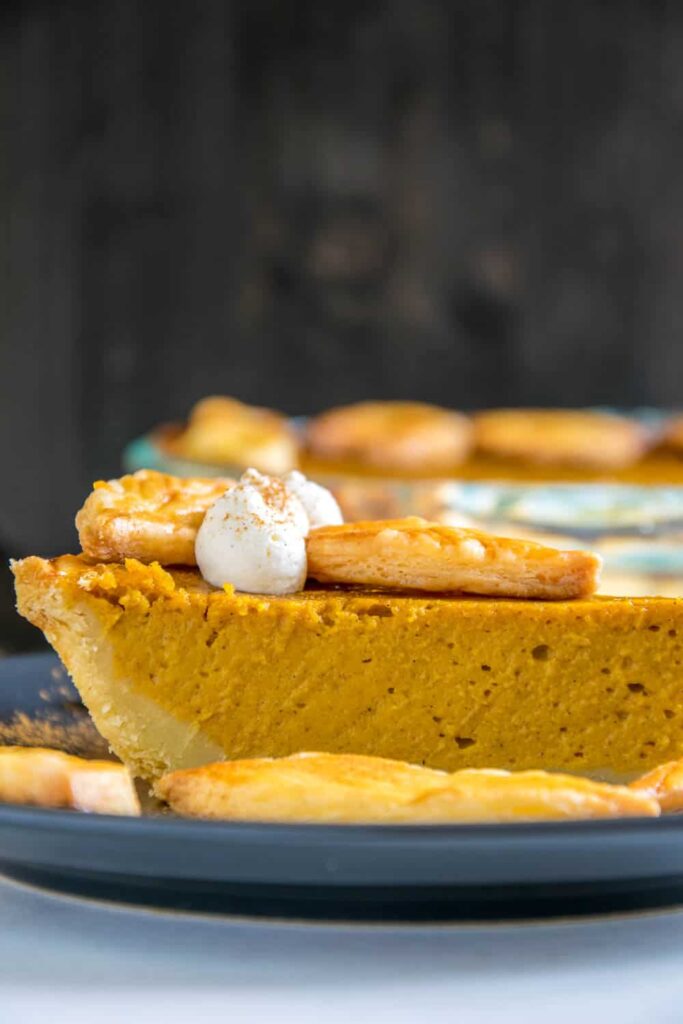 Ein Stück Pumpkin Pie mit Herbstblätter-Deko und Zimt-Sahne