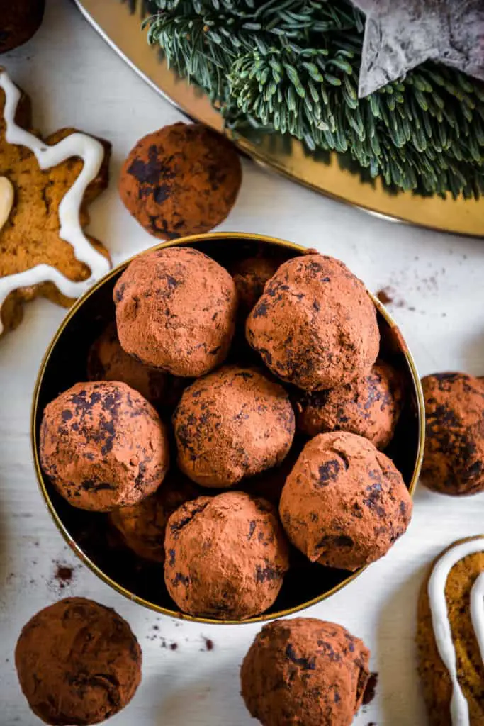 Saftige Gingerbread Energy Bites aus getrockneten Feigen, Pflaumen, Mandeln, Walnüssen, Mandelmus und Lebkuchengewürz in einer goldenen Schale mit Lebkuchen und Adventkranz als Dekoration