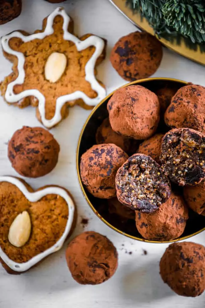 Saftige Gingerbread Energy Bites aus getrockneten Feigen, Pflaumen, Mandeln, Walnüssen, Mandelmus und Lebkuchengewürz in einer goldenen Schale mit Lebkuchen und Adventkranz als Dekoration