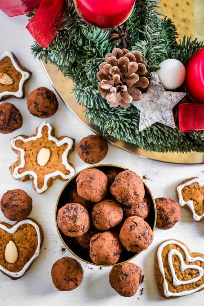 Saftige Gingerbread Energy Bites aus getrockneten Feigen, Pflaumen, Mandeln, Walnüssen, Mandelmus und Lebkuchengewürz in einer goldenen Schale mit Lebkuchen und Adventkranz als Dekoration