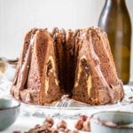 Nougatgugelhupf mit Cheesecake-Nutella-Kern und einer Glasur aus Nougatschokolade und Nutella, bestreut mit Haselnusskrokant und gehackter Nougatschokolade