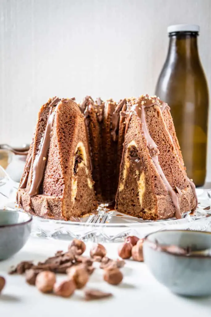 Nougatgugelhupf mit Cheesecake-Nutella-Kern und einer Glasur aus Nougatschokolade und Nutella, bestreut mit Haselnusskrokant und gehackter Nougatschokolade