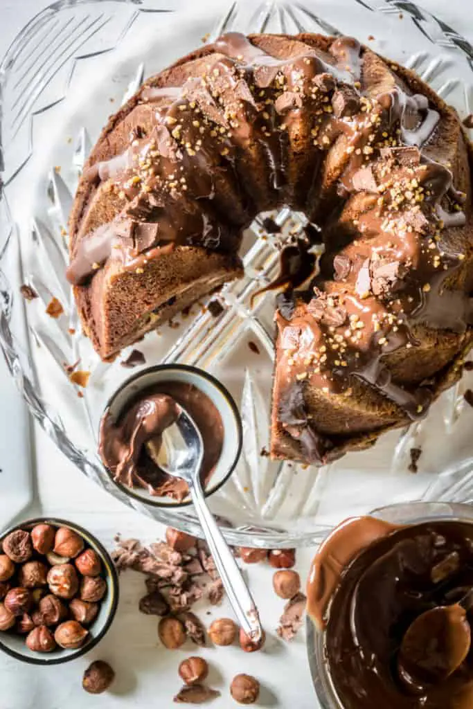 Nougatgugelhupf mit Cheesecake-Nutella-Kern und einer Glasur aus Nougatschokolade und Nutella, bestreut mit Haselnusskrokant und gehackter Nougatschokolade