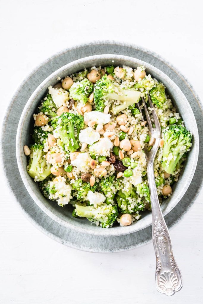 Grüne Couscous-Kichererbsenpfanne mit Feta, Pinienkernen, Brokkoli, Erbsen und Rosinen