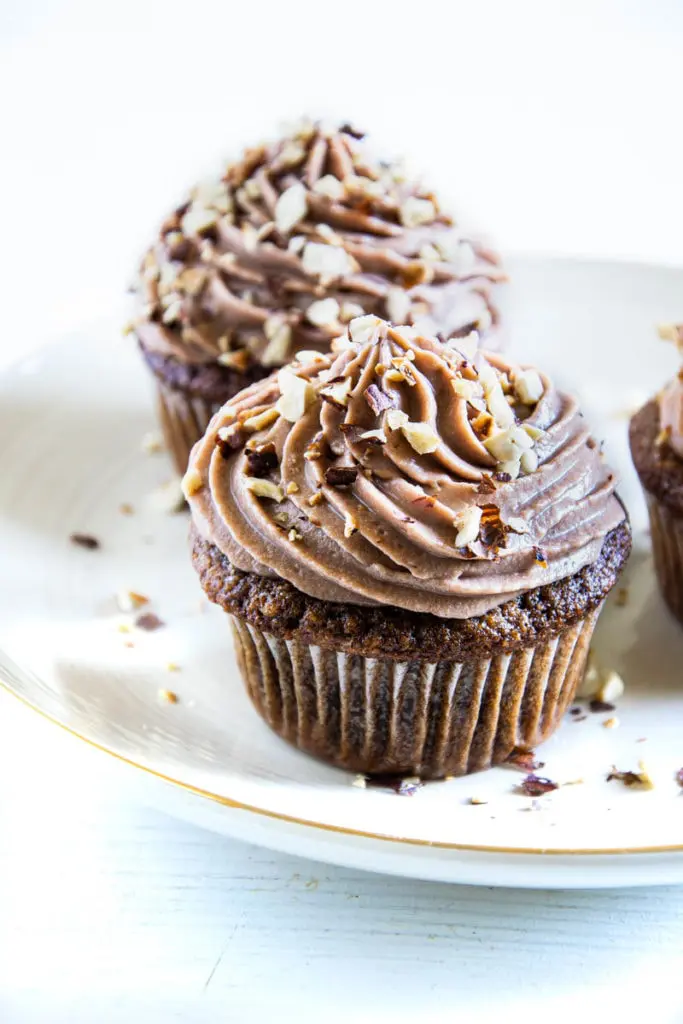 Zwei Haselnuss-Nougat-Cupcakes hintereinander auf einem hellen Teller