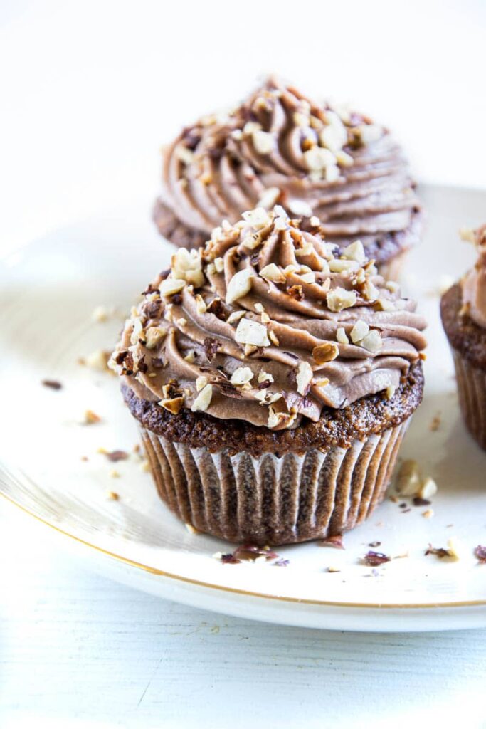 Zwei Haselnuss-Nougat-Cupcakes hintereinander auf einem hellen Teller