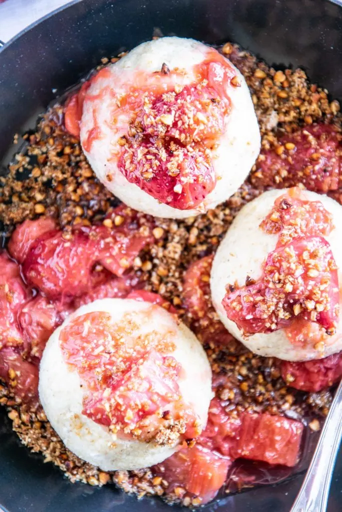 Gesunde Erdbeerknödel mit Buchweizen-Kokos-Crunch in einer schwarzen Servierpfanne.