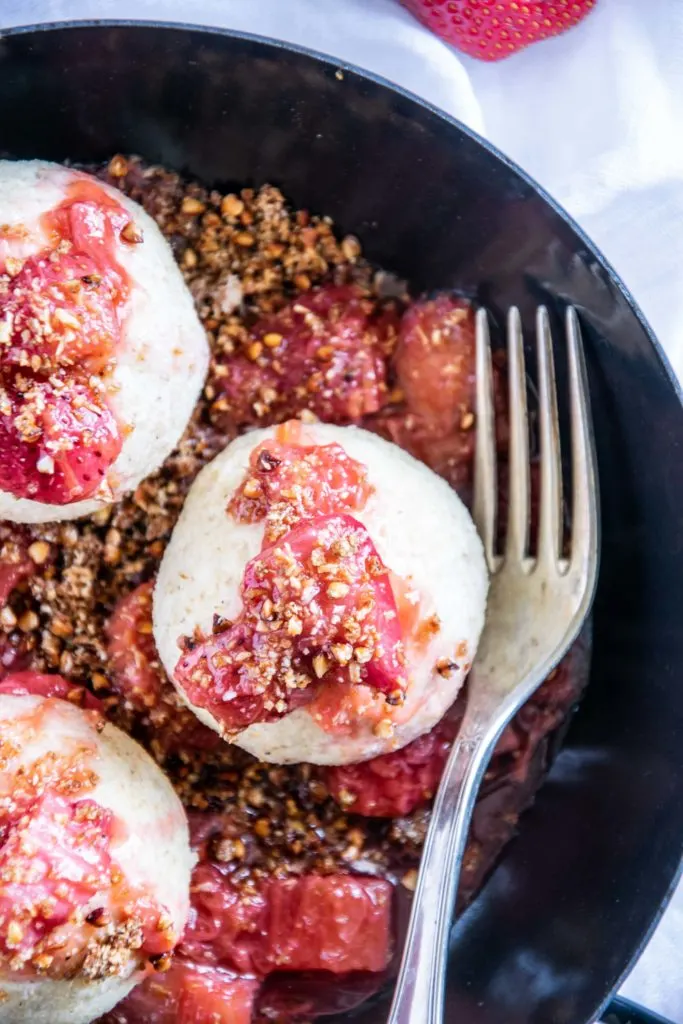 Gesunde Erdbeerknödel mit Buchweizen-Kokos-Crunch in einer schwarzen Servierpfanne.