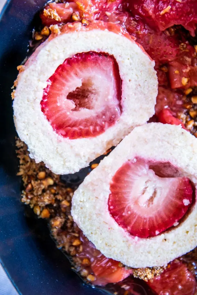 Ein halbierter Erdbeerknödel mit Buchweizen-Kokos-Crunch und Erdbeer-Rhabarberkompott in der Nahaufnahme.