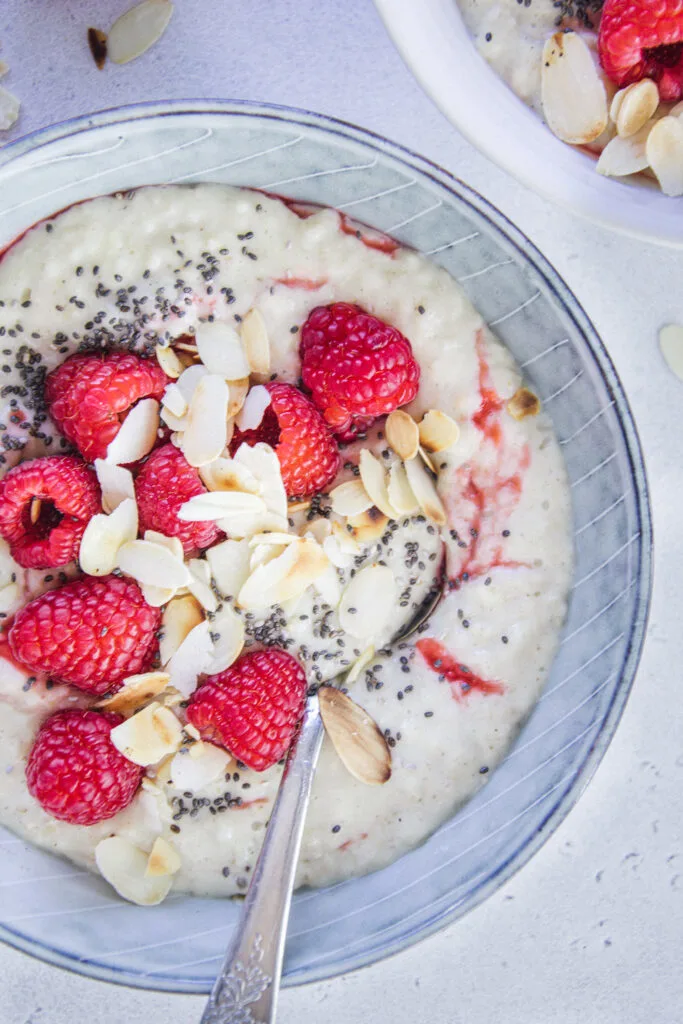 Pudding-Porridge mit ger&ouml;steten Mandebl&auml;ttchen, Himbeeren und Chiasamen.