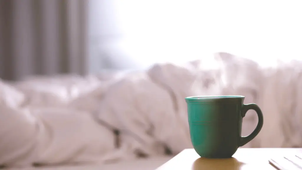Grüne Kaffeetasse mit Bett im Hintergrund.