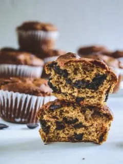 Ein halbierter Peanut Chocolate Chip Muffins mit der Textur im Fokus und weiteren Muffins im Hintergrund. Fotografiert auf Augenhöhe.