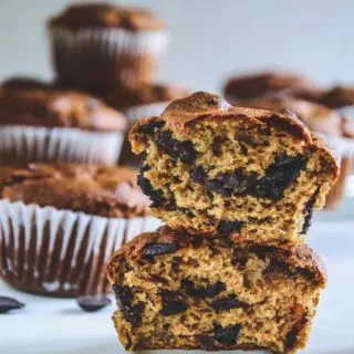 Ein halbierter Peanut Chocolate Chip Muffins mit der Textur im Fokus und weiteren Muffins im Hintergrund. Fotografiert auf Augenhöhe.