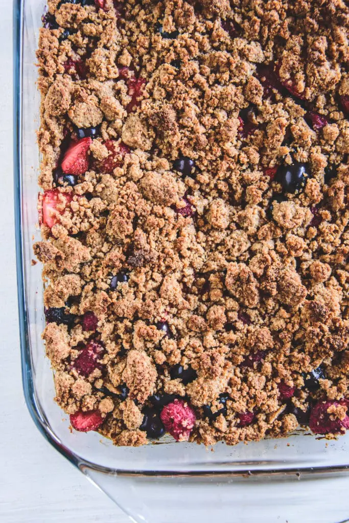 Gesunder Beeren-Streuselkuchen mit Dinkelmehl, Mandeln und ohne Zucker in einer Glasform. Ansicht von oben.