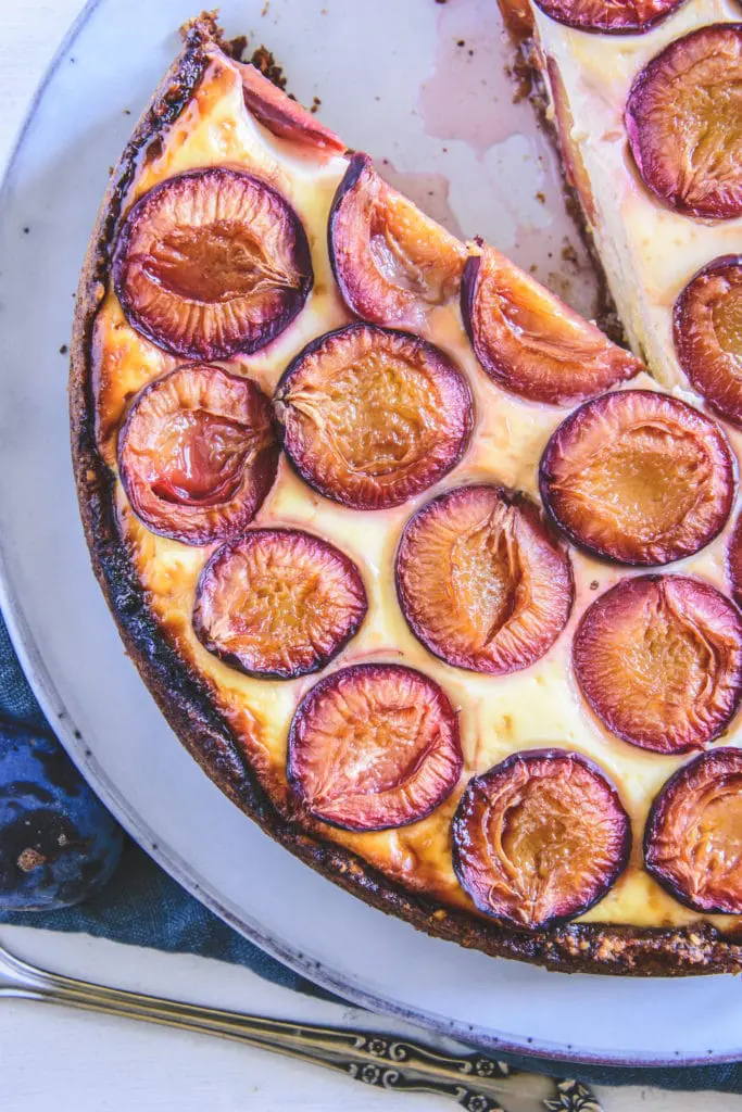 Angeschnittener Zwetschgenkuchen mit Topfen und Nüssen im Top View. Die Schnittseiten der Zwetschgen zeigen nach oben.