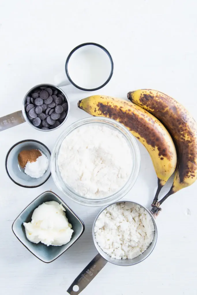 Zutaten für Banane-Schoko-Protein-Tassenkuchen in Schüssel auf weißem Untergrund. Flatlay.