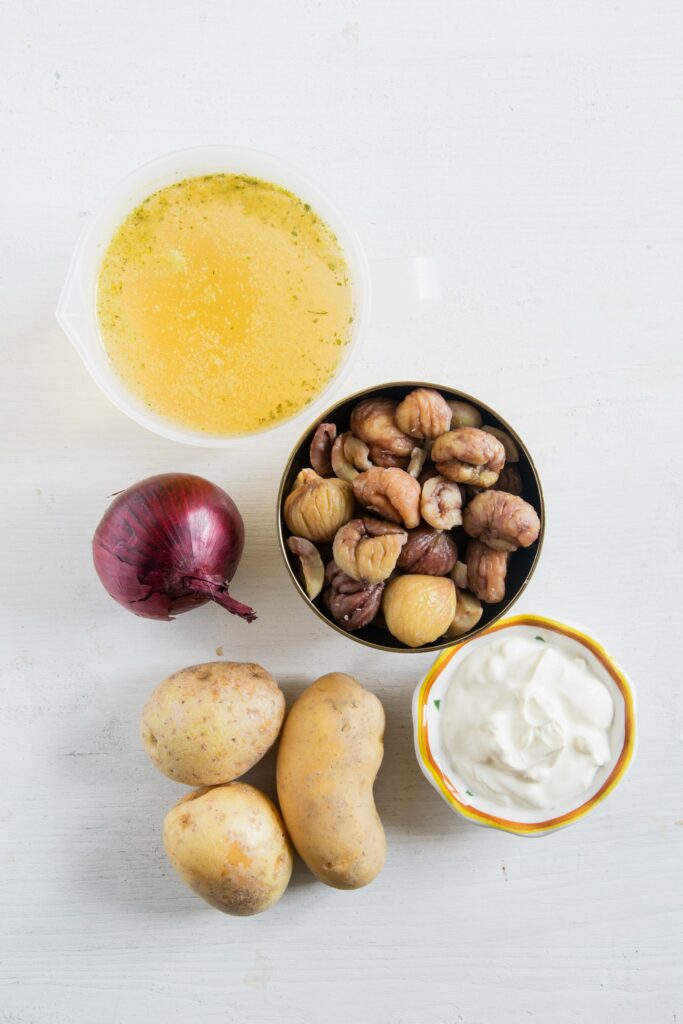 Zutaten für die Maroni-Kartoffelsuppe auf weißem Untergrund. Flatlay.