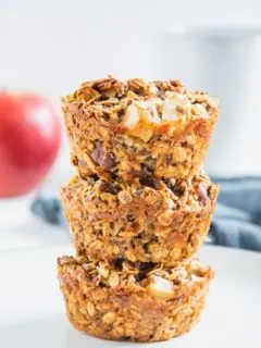 Drei Oatmeal Muffins mit Apfel und Nüssen gestapelt übereinander. Aufnahme von vorne auf Augenhöhe. Sehr viele Details erkennbar.