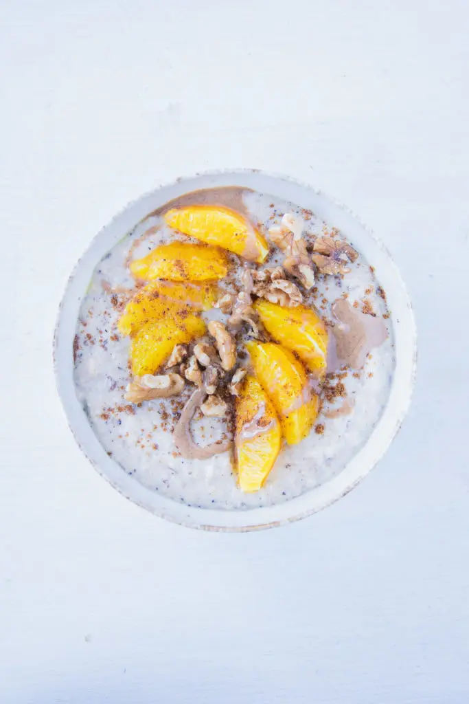 Porridge getoppt mit Orangenspalten, Walnüssen, Lebkuchengewürz und Haselnussmus. Aufnahme von oben.