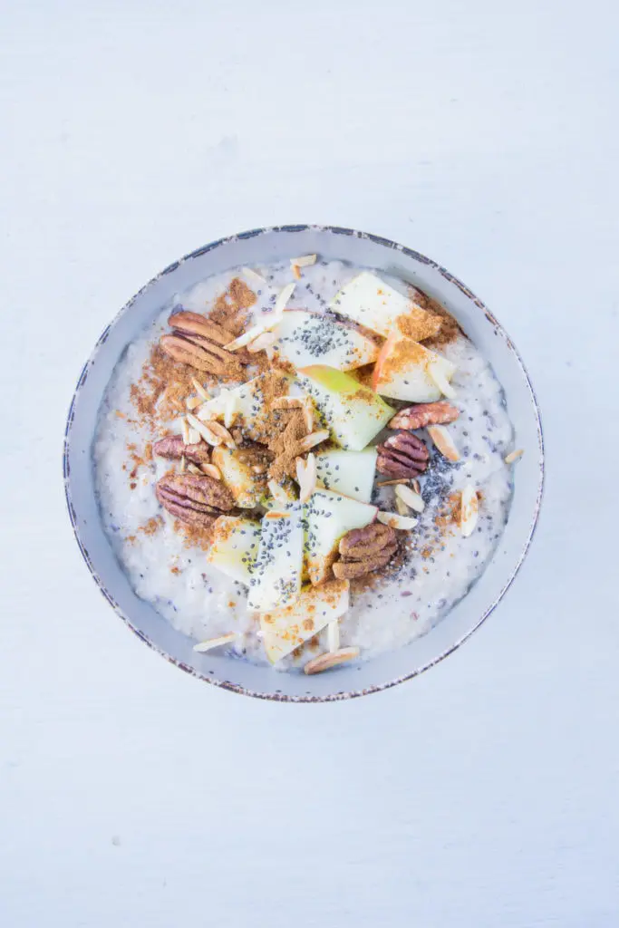 Porridge getoppt mit Apfel, Mandelsplittern, Pekannusskernen, Zimt und Chiasamen