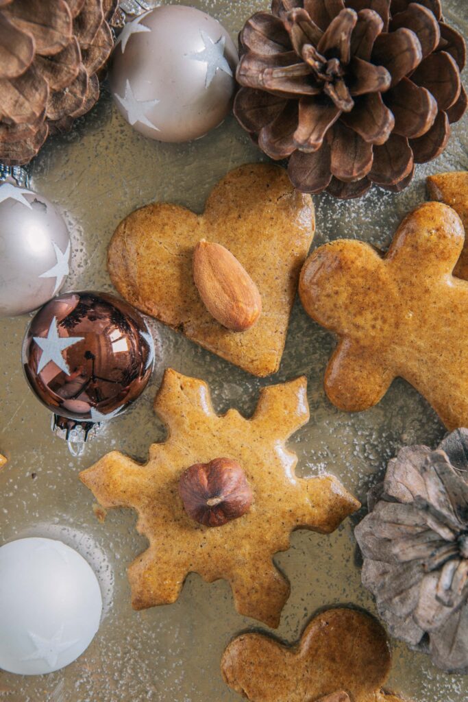 Gesündere Lebkuchen auf einem goldenen Teller, dekoriert mit kleinen Christbaumkugeln und Zapfen. Nahaufnahme von oben.