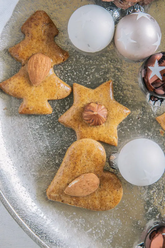 Gesündere Lebkuchen auf einem goldenen Teller, dekoriert mit kleinen Christbaumkugeln. Nahaufnahme von oben.