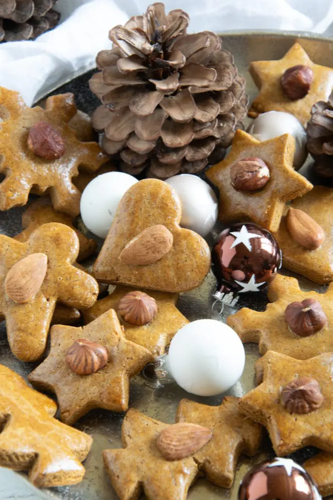 Gesündere Lebkuchen im 45-Grad-Winkel auf einem goldenen Teller, dekoriert mit kleinen Christbaumkugeln und Zapfen.