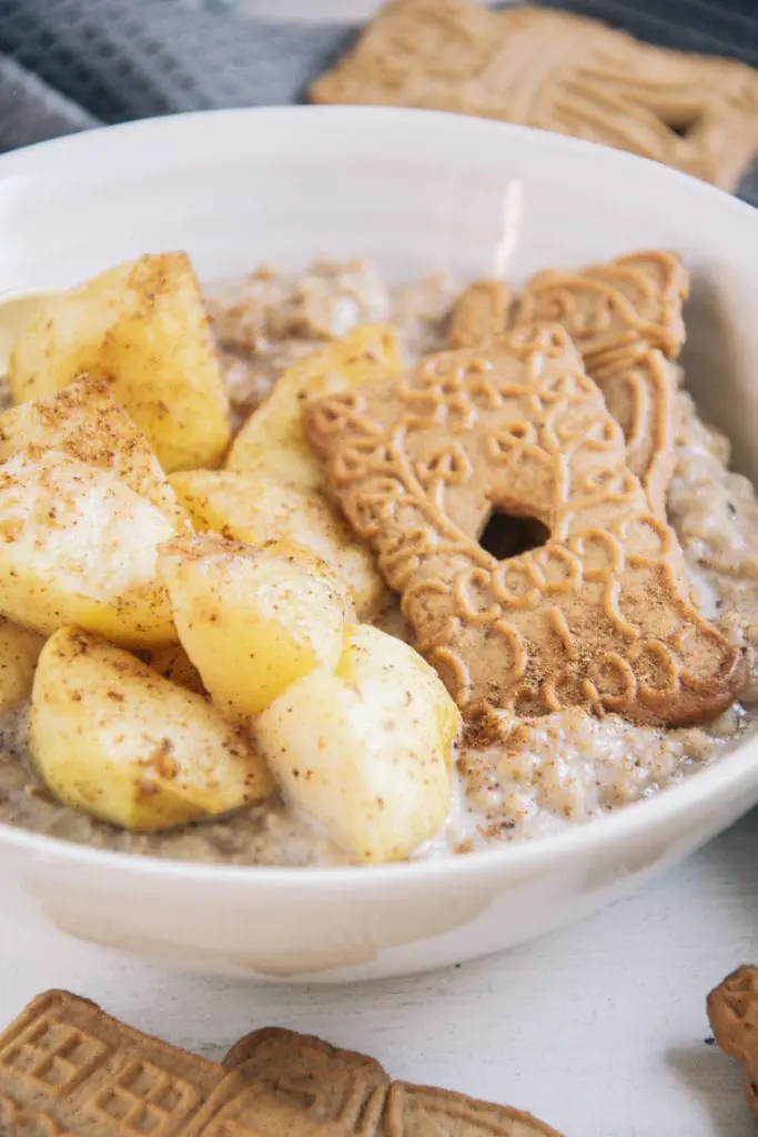 Nahaufnahme von Bratapfelstücken und Spekulatiuskeksen auf cremigem Spekulatius-Porridge im 45-Grad-Winkel.