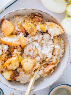 Mit einem goldenen Löffel durchgerührter Apfelstrudel-Porridge. Nahaufnahme von oben, sodass die cremige Konsistenz deutlich sichtbar ist.