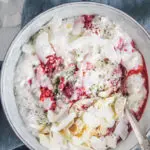 Low carb Himbeer-Kokos-Hanf Frühstücksbrei in einer graublauen Schüssel auf einem dunkelblauen Leinentuch