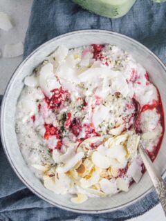 Low carb Himbeer-Kokos-Hanf Frühstücksbrei in einer graublauen Schüssel auf einem dunkelblauen Leinentuch