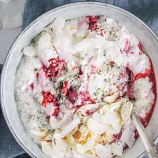 Low carb Himbeer-Kokos-Hanf Frühstücksbrei in einer graublauen Schüssel auf einem dunkelblauen Leinentuch