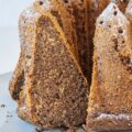 Angeschnittener Low carb Mohnkuchen auf Augenhöhe fotografiert. Ein Stück lehnt in der Schnittöffnung des Gugelhupfs, sodass alle Details gut erkennbar sind.