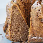 Angeschnittener Low carb Mohnkuchen auf Augenhöhe fotografiert. Ein Stück lehnt in der Schnittöffnung des Gugelhupfs, sodass alle Details gut erkennbar sind.