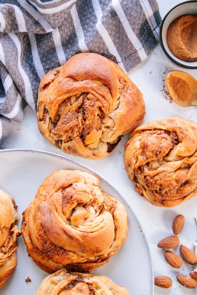 Mandel-Zimtknoten nach dem Grundrezept für veganen süßen Hefeteig ohne Zucker von oben auf graublauen Tellern fotografiert.