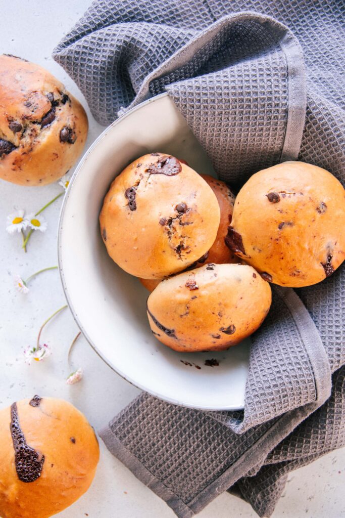 Schokobrötchen nach dem Grundrezept für veganen süßen Hefeteig ohne Zucker in einer graublauen Steingut-Schüssel mit einem grauen Küchentuch. Aufnahme von oben.