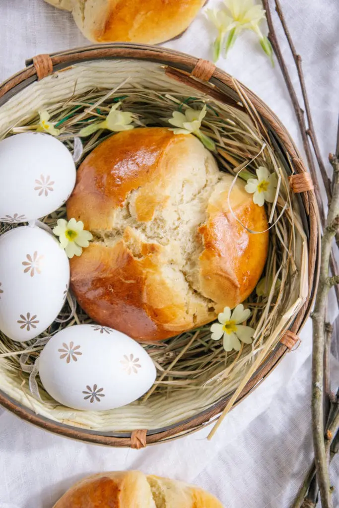 Dinkel-Osterpinze ohne Zucker in einem Osternest mit drei Ostereiern und Schlüsselblumen. Aufnahme von oben.