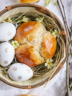 Dinkel-Osterpinze ohne Zucker in einem Osternest mit drei Ostereiern und Schlüsselblumen. Aufnahme von oben.