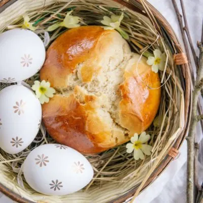 Dinkel-Osterpinze ohne Zucker in einem Osternest mit drei Ostereiern und Schlüsselblumen. Aufnahme von oben.